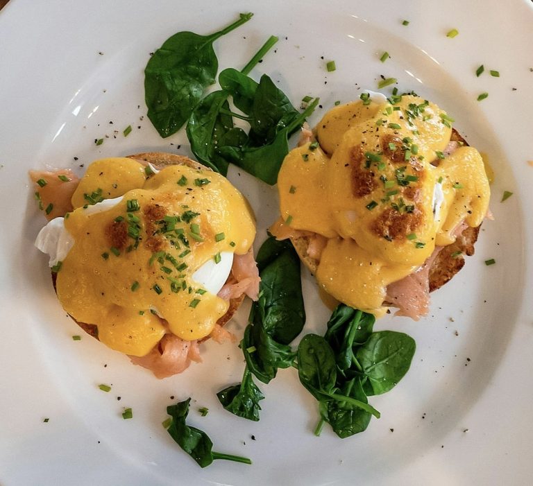 Classic eggs Benedict with creamy hollandaise sauce over poached eggs and Canadian bacon on toasted English muffins.